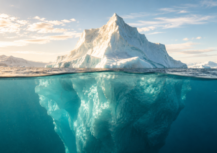 A real iceberg in bright daylight, its waterline clearly visible, embodying the Iceberg Model's central metaphor as a photographic scene.